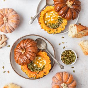 pumpkins cut open like a bowl and pilled with soup and topped with pepitas