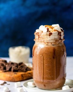 mason jar filled with a chocolate drink and topped with marshmallows and drizzled chocolate