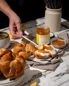croissants being covered in marmalade with a hand