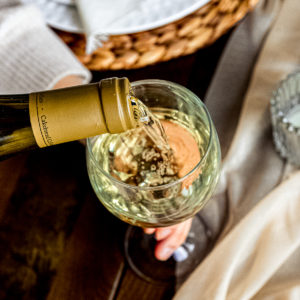 overhead shot of white wine being poured into wine glass