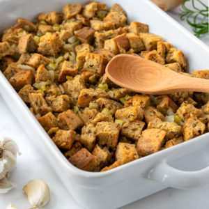 stuffing in a white dish with a wooden spoon on a white counter