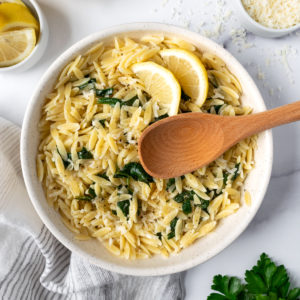pasta in a large white bowl with wooden spoon