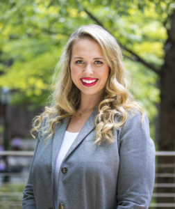 woman in grey blazer with red lipstick smiling at the camera