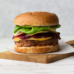turkey burger with toppings on a white sheet and brown board