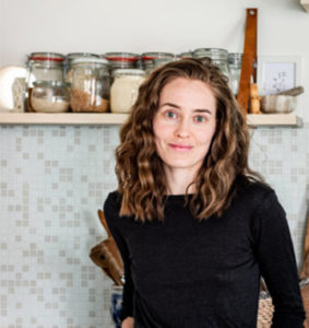 woman standing in a kitchen with jars behind her