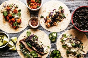 tacos laid on a surface with bowls of toppings