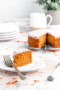 a slice of cake on a plate with a fork and cake behind it