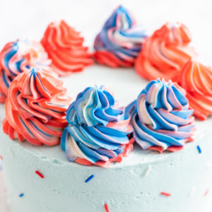 blue cake with red and blue swirl frosting and sprinkles