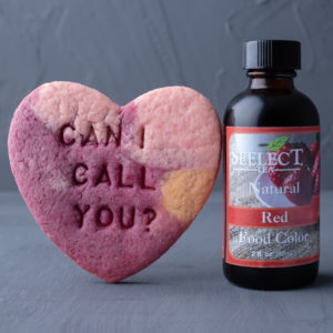 bottle of Seelect Tea natural red food coloring next to a pink cookie that says "can I call you?"