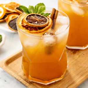 drink with cinnamon sticks, sliced dried oranges, and garnish in a cup