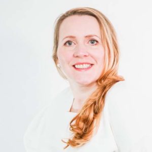 woman in a white shirt and blonde hair smiling with a white background