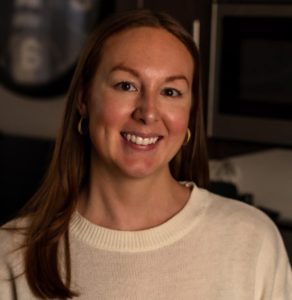 woman with a white sweater and brown hair smiling