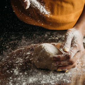 woman spreading flour on dough
