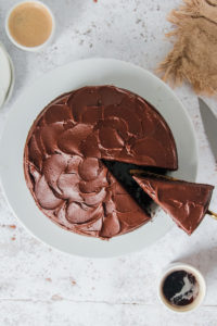 chocolate buttermilk cake being sliced on a white plate