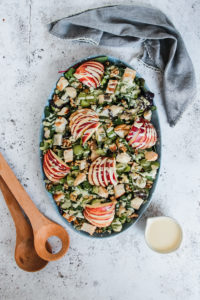 waldord salad with toppings in a bowl next to salad dressing