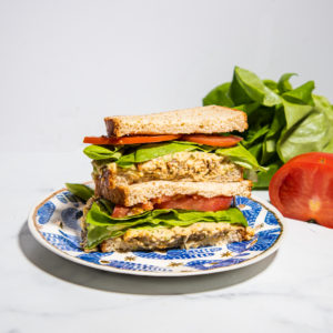 half of sandwiches stacked ontop of each other with tomatoes and lettuce on a plate