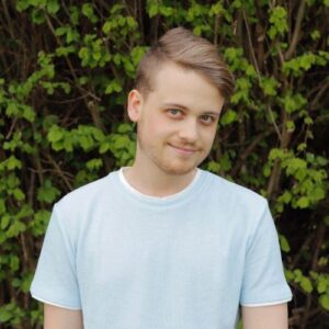 man with blonde hair wearing a white shirt and smiling to the camera