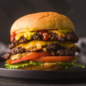 double patty cheeseburger with tomatoes, lettuce, and different toppings