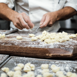 man holding a fork in front of a cutting board of flour and dough