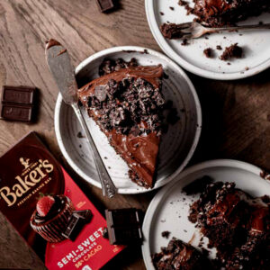 overhead shot of a slice of chocolate cake next to other plates of chocolate cake and a semi-sweet chocolate bar