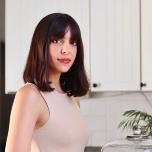 woman in kitchen with tank top and shouldr length brown hair