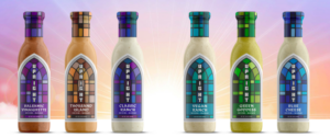 Six bottles of Upright salad dressings with stained-glass-inspired labels showcasing different flavors: Balsamic Vinaigrette, Thousand Island, Classic Ranch, Vegan Ranch, Green Goddess, and Blue Cheese, set against a radiant pastel background.
